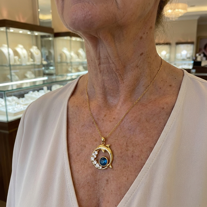 Goldene Halskette mit Delfin und Kristall am Hals getragen